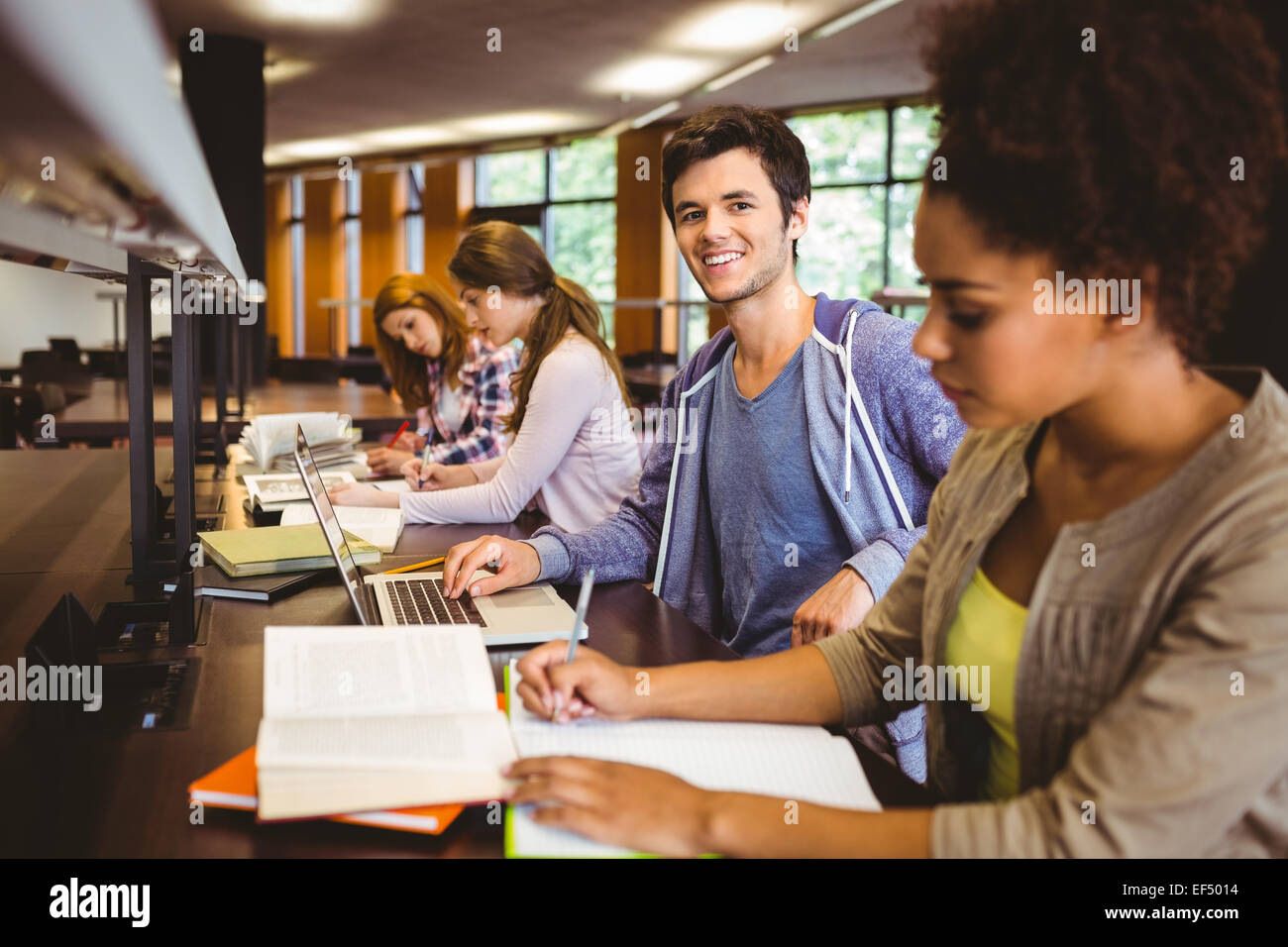 Student looking at camera while studying with classmates Stock Photo ...