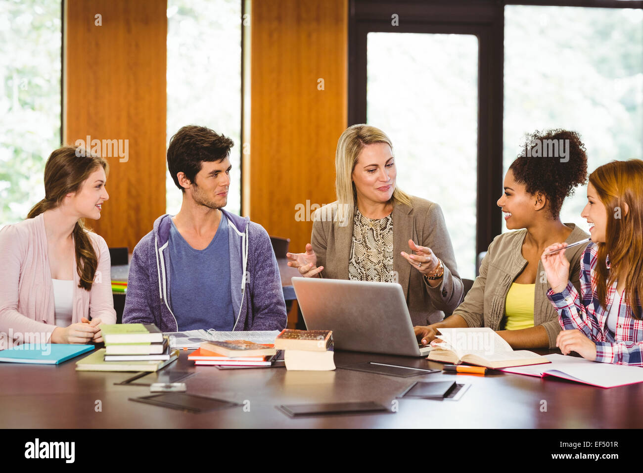 Smiling female with students and teacher in library Stock Photo - Alamy