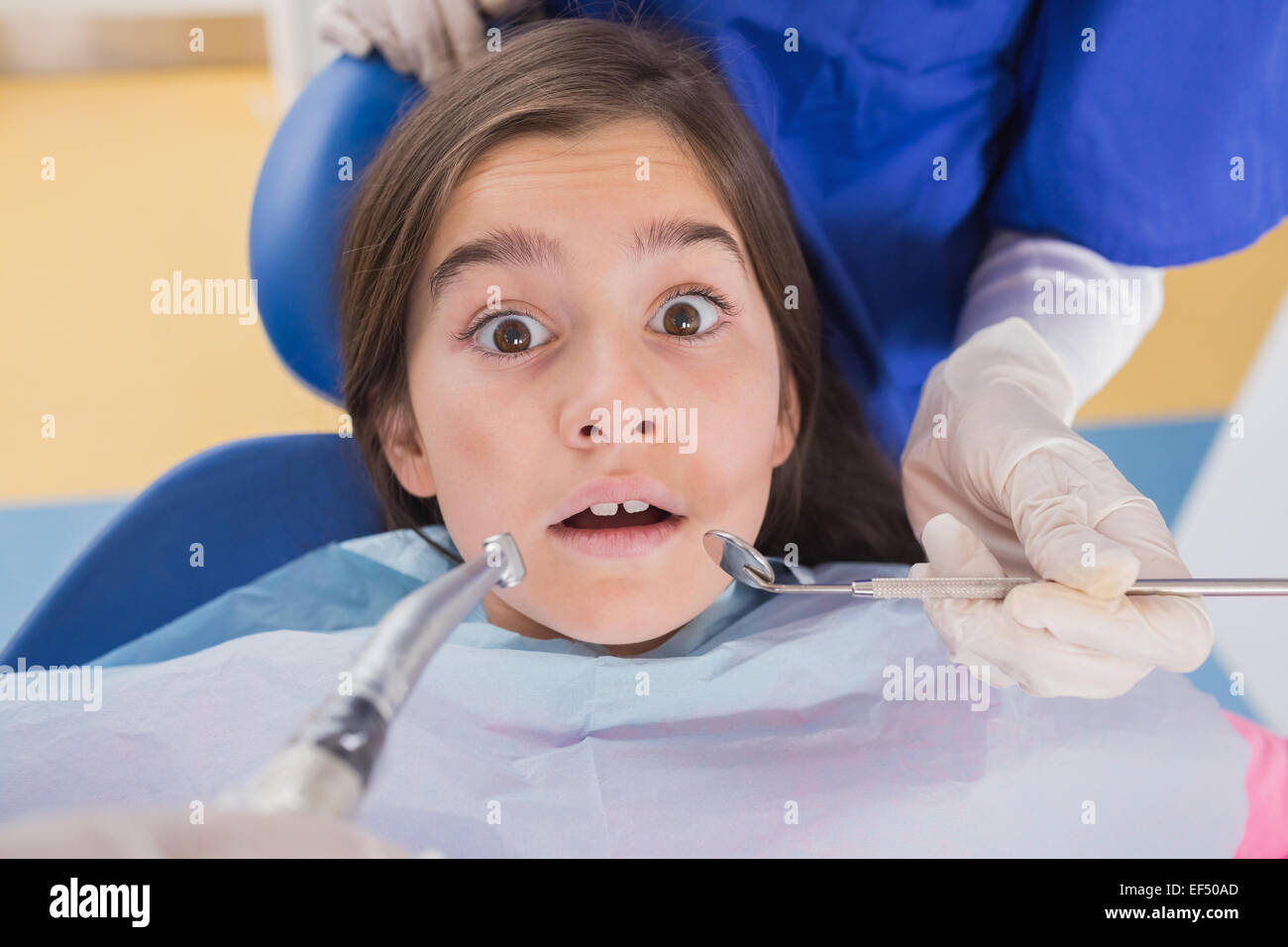 Dentist and his dental assistant examining a terrified young patient