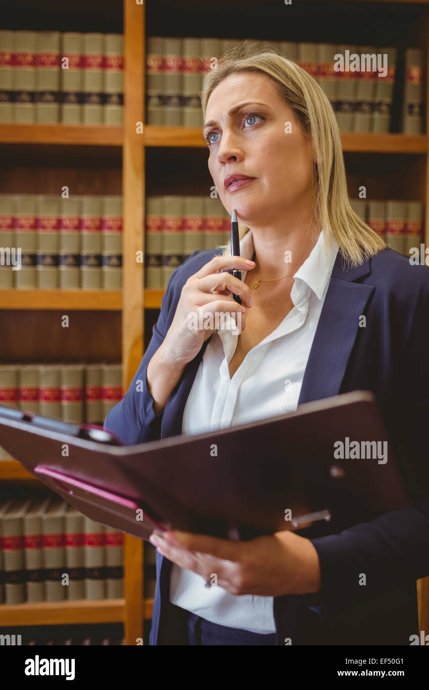 Thinking female librarian holding textbook Stock Photo