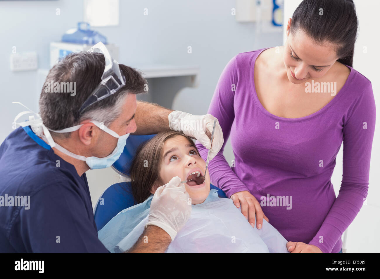 Pediatric dentist examining young patient with her mother Stock Photo