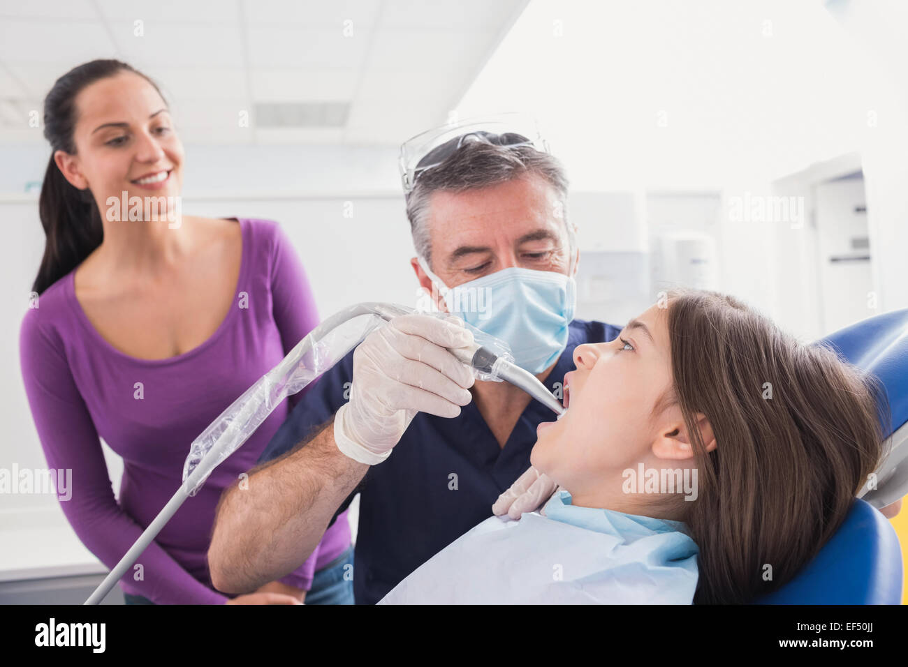 Pediatric dentist examining young patient with a suction tube Stock