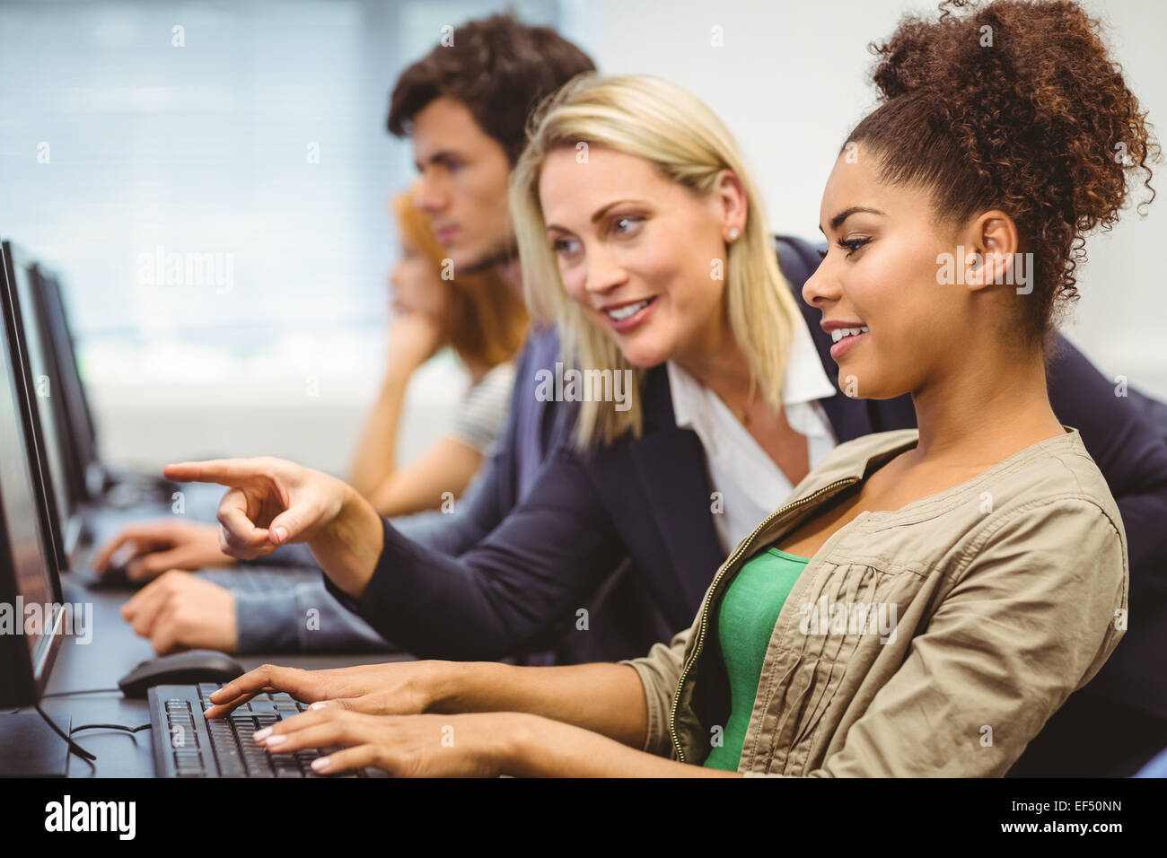 Attractive teacher talking to her student in computer class Stock Photo