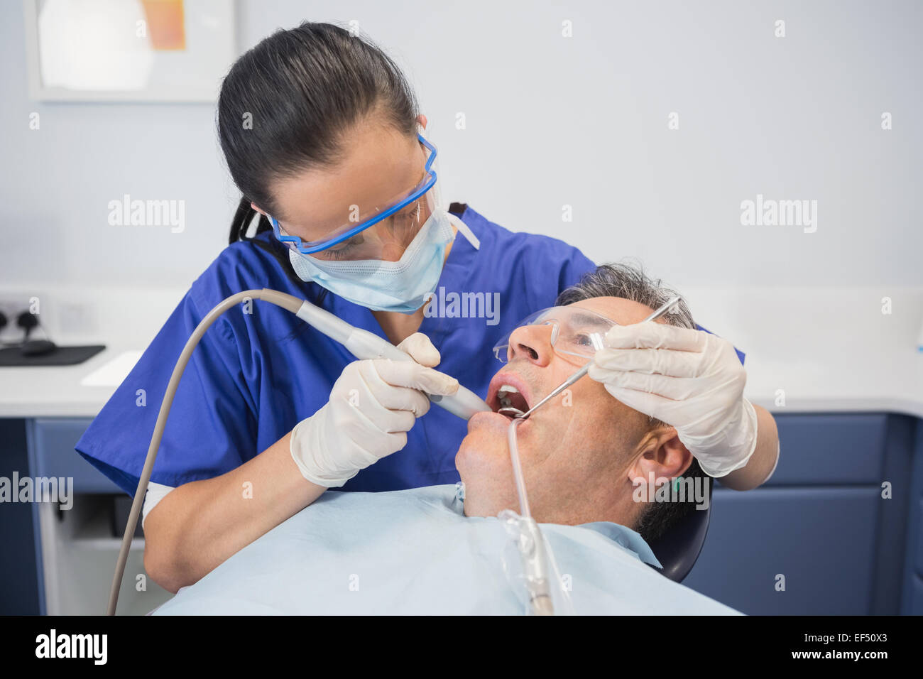 Dentist examining a patient with suction hose Stock Photo Alamy