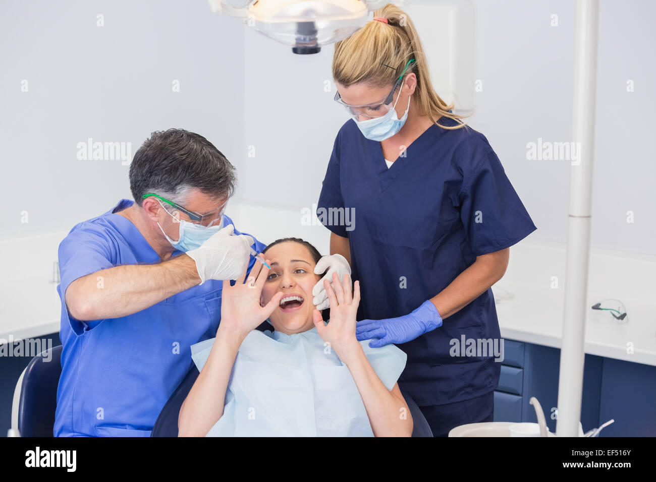Dentist doing injection and patient protesting Stock Photo