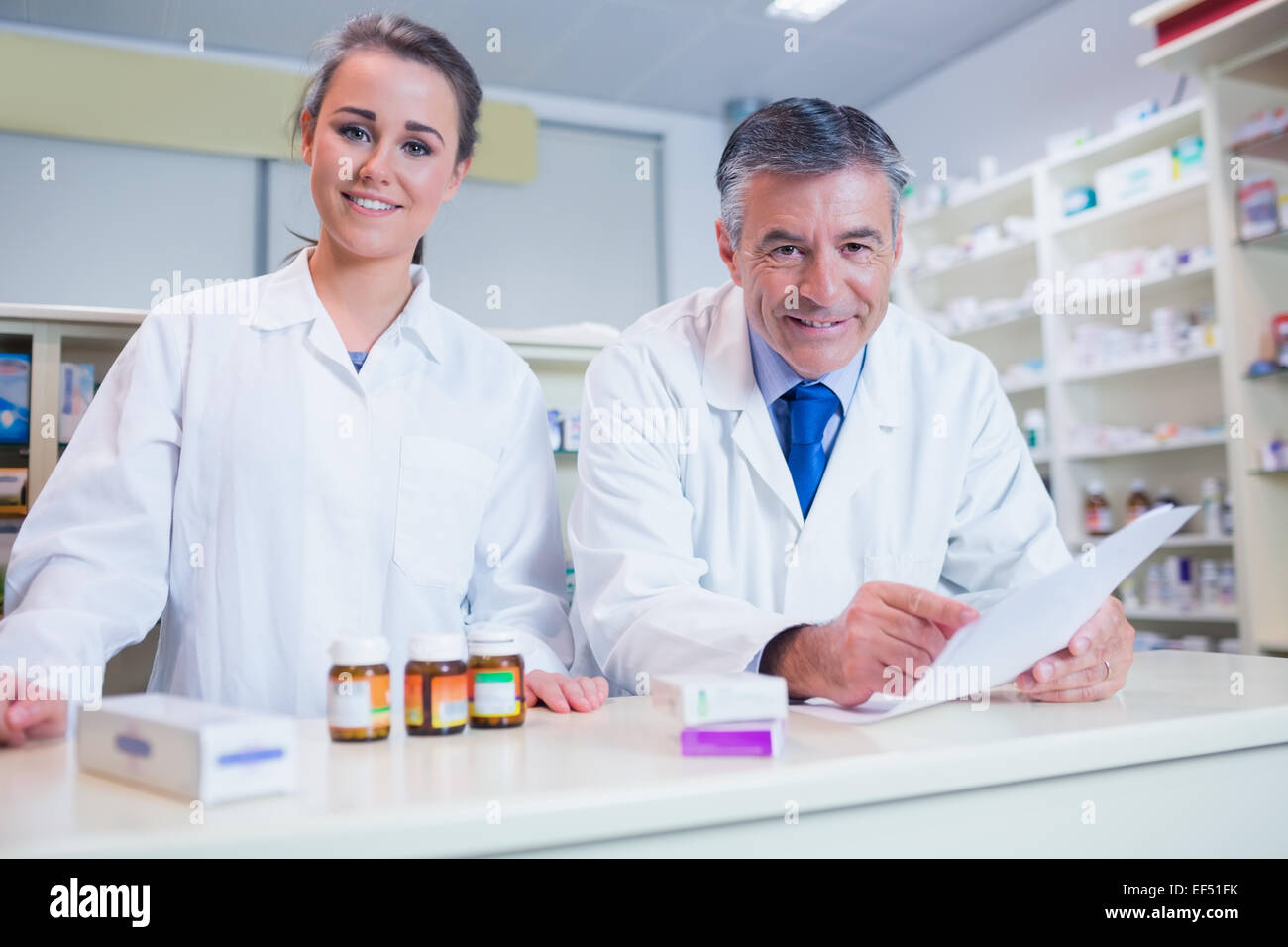 Pharmacist holding a prescription next to his trainee Stock Photo