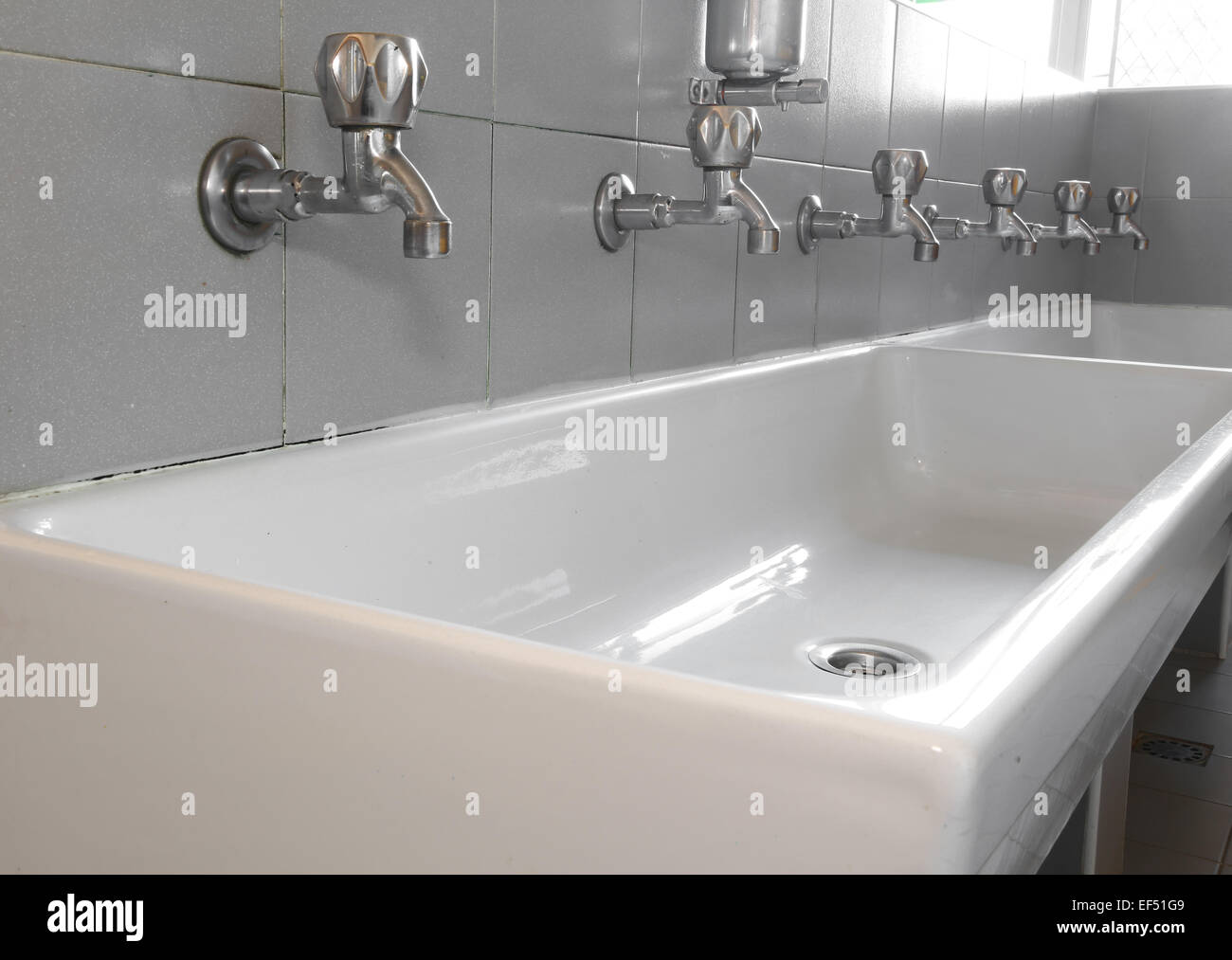 series of steel taps in white ceramic sink Stock Photo