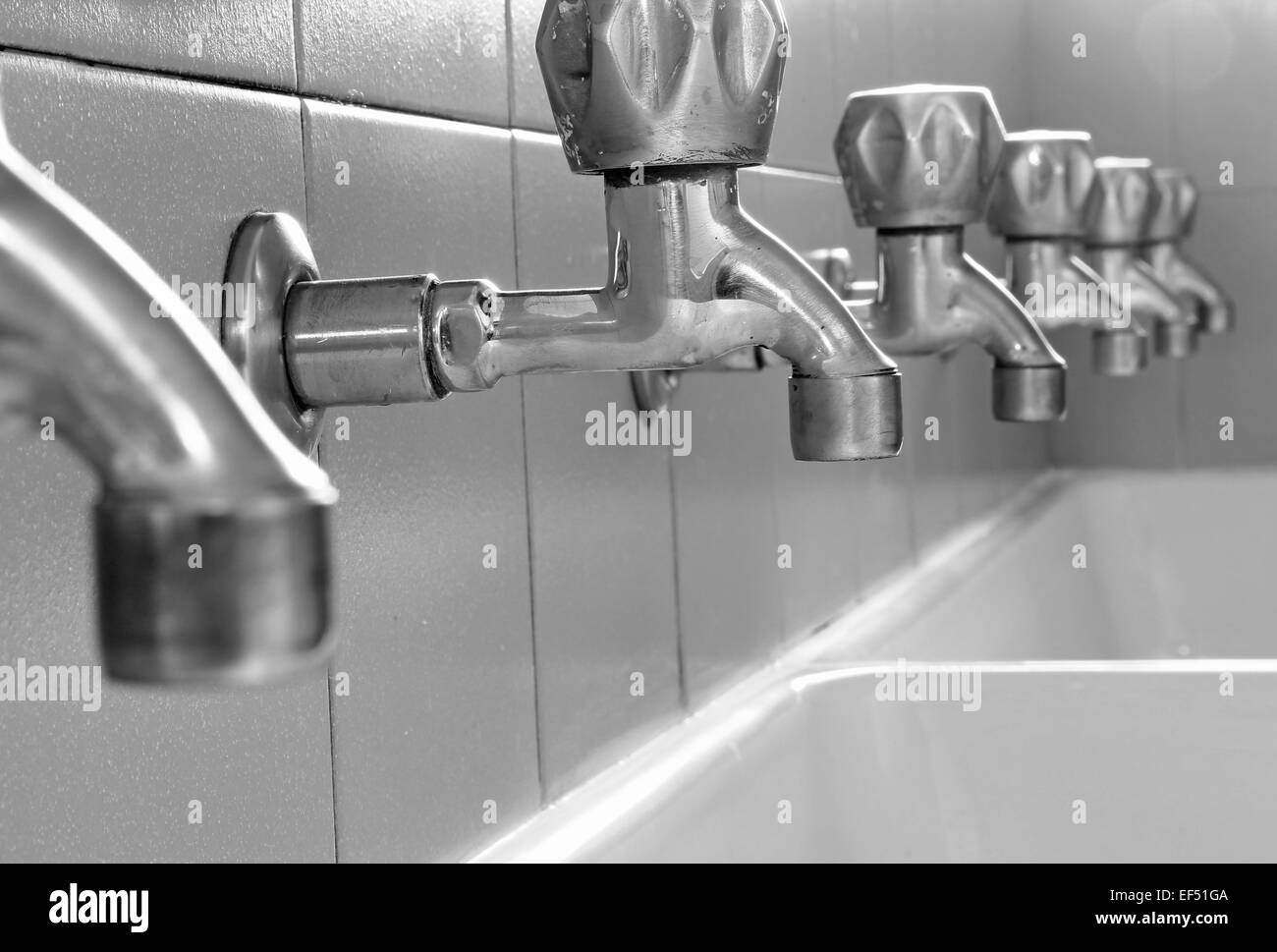 many steel taps in white ceramic sink Stock Photo