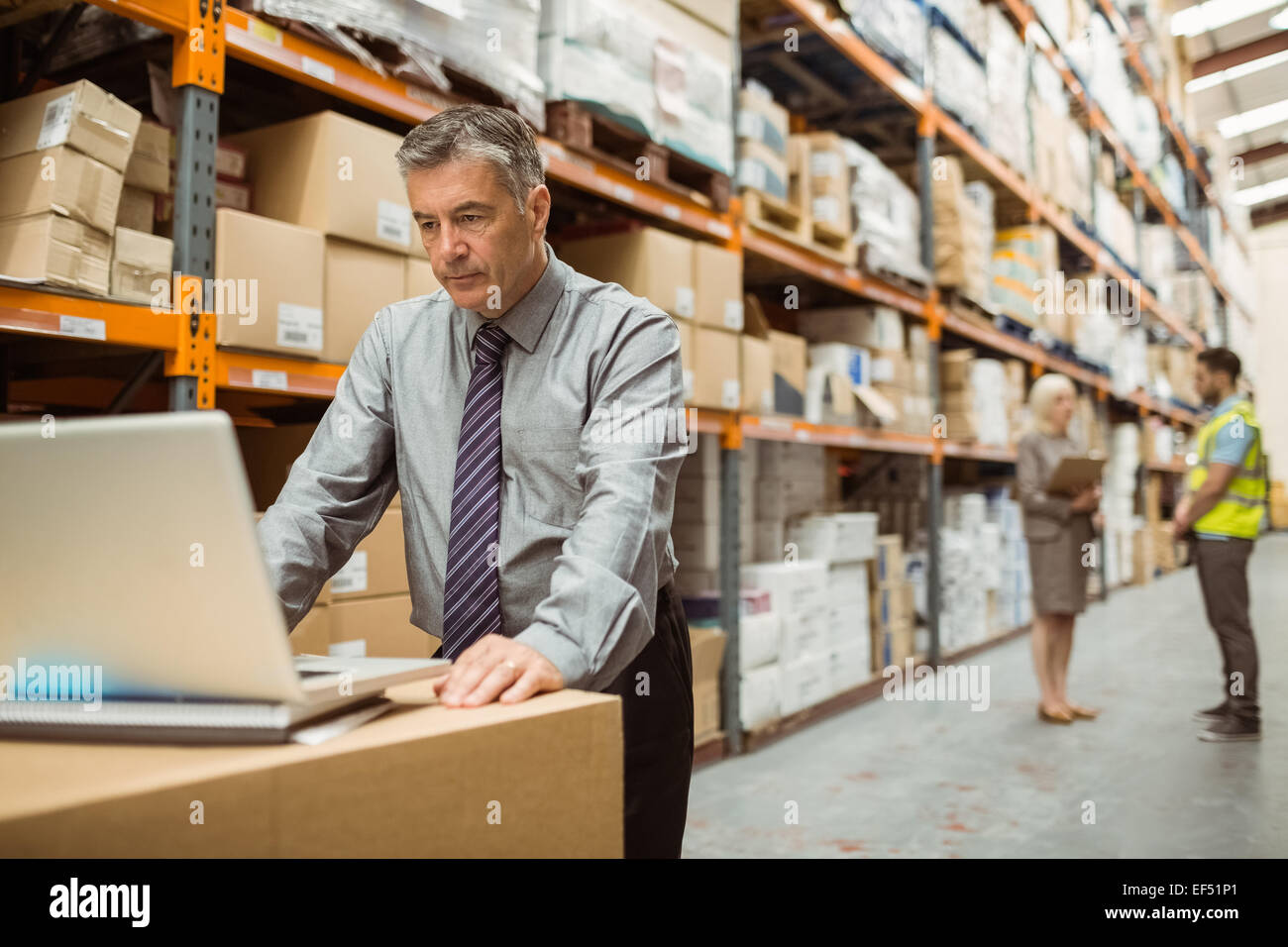 Focused warehouse manager working on laptop Stock Photo - Alamy