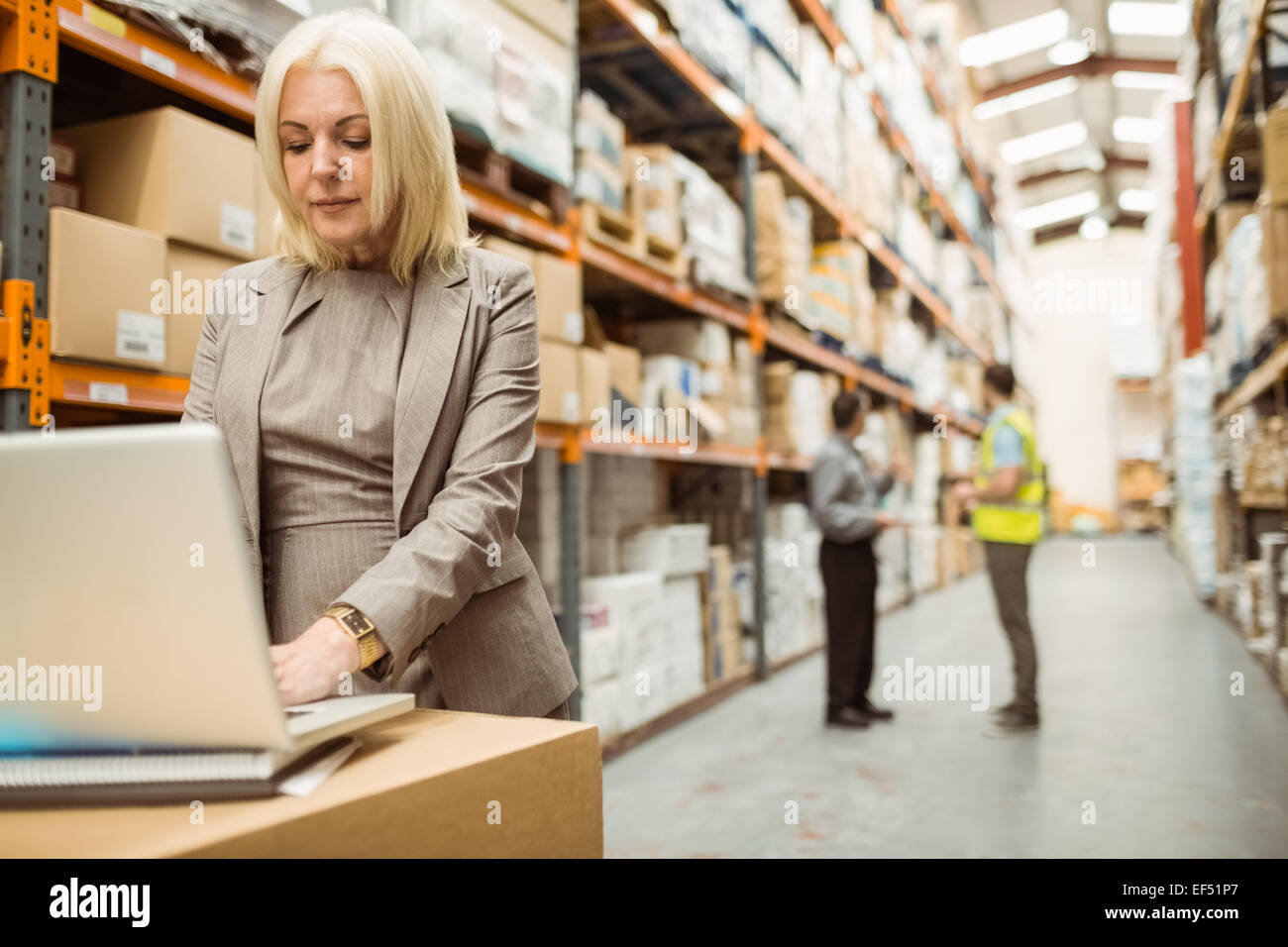 Focused warehouse manager working on laptop Stock Photo - Alamy