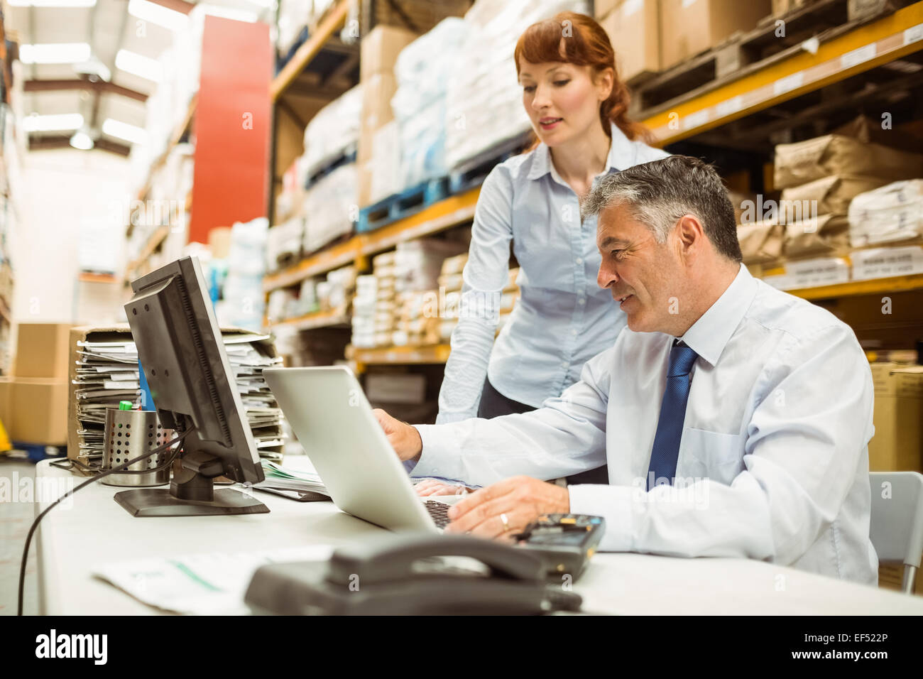 Warehouse managers working together on laptop Stock Photo - Alamy