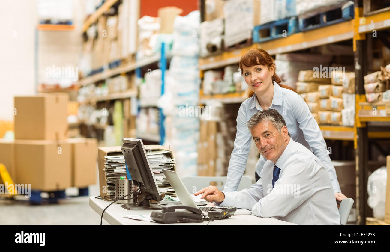 Warehouse managers working together on laptop Stock Photo - Alamy