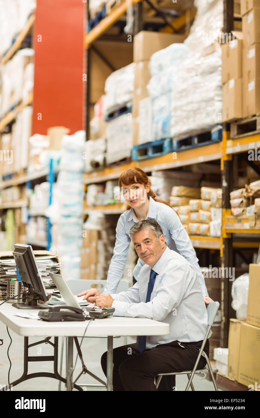 Warehouse managers working together on laptop Stock Photo - Alamy