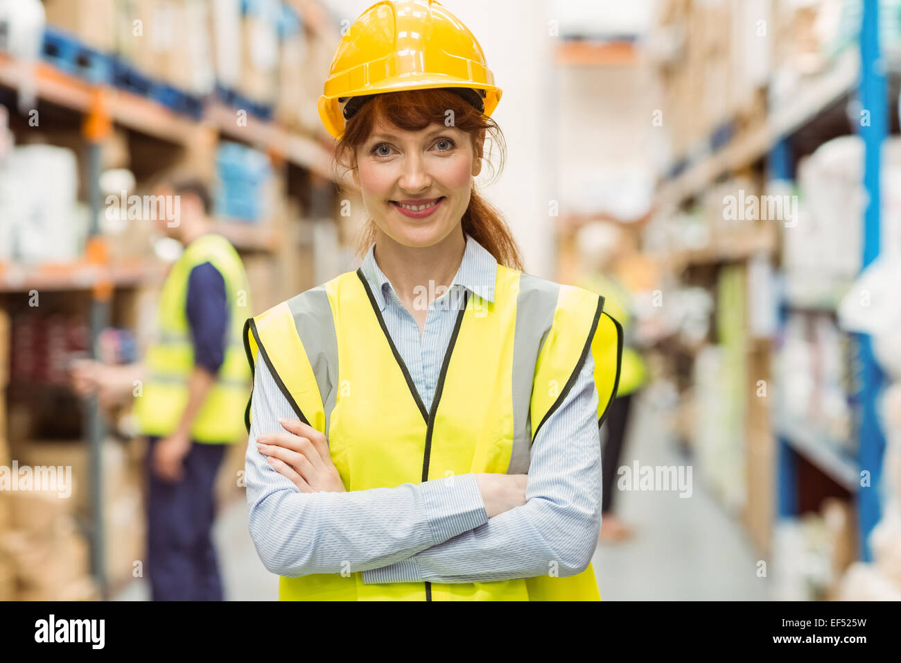 Warehouse manager smiling at camera with arms crossed Stock Photo - Alamy
