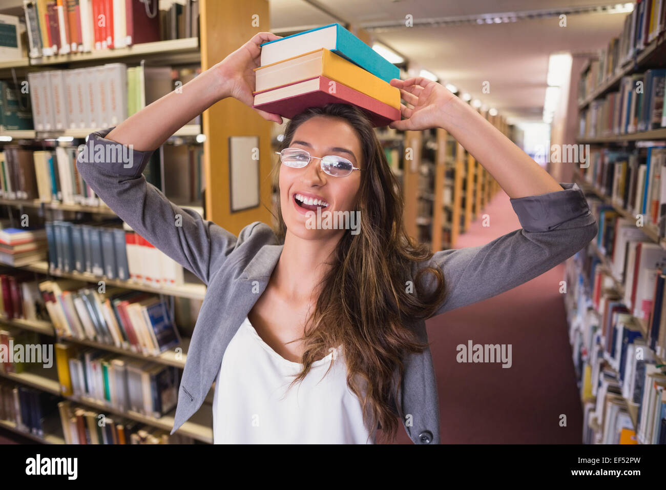 Pretty student holding books in library Stock Photo - Alamy