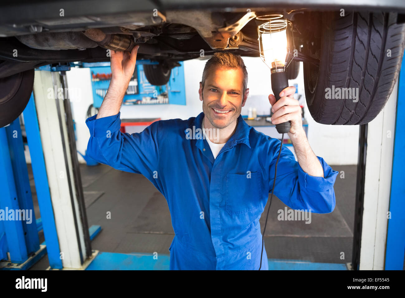 Mechanic using torch to look under car Stock Photo Alamy