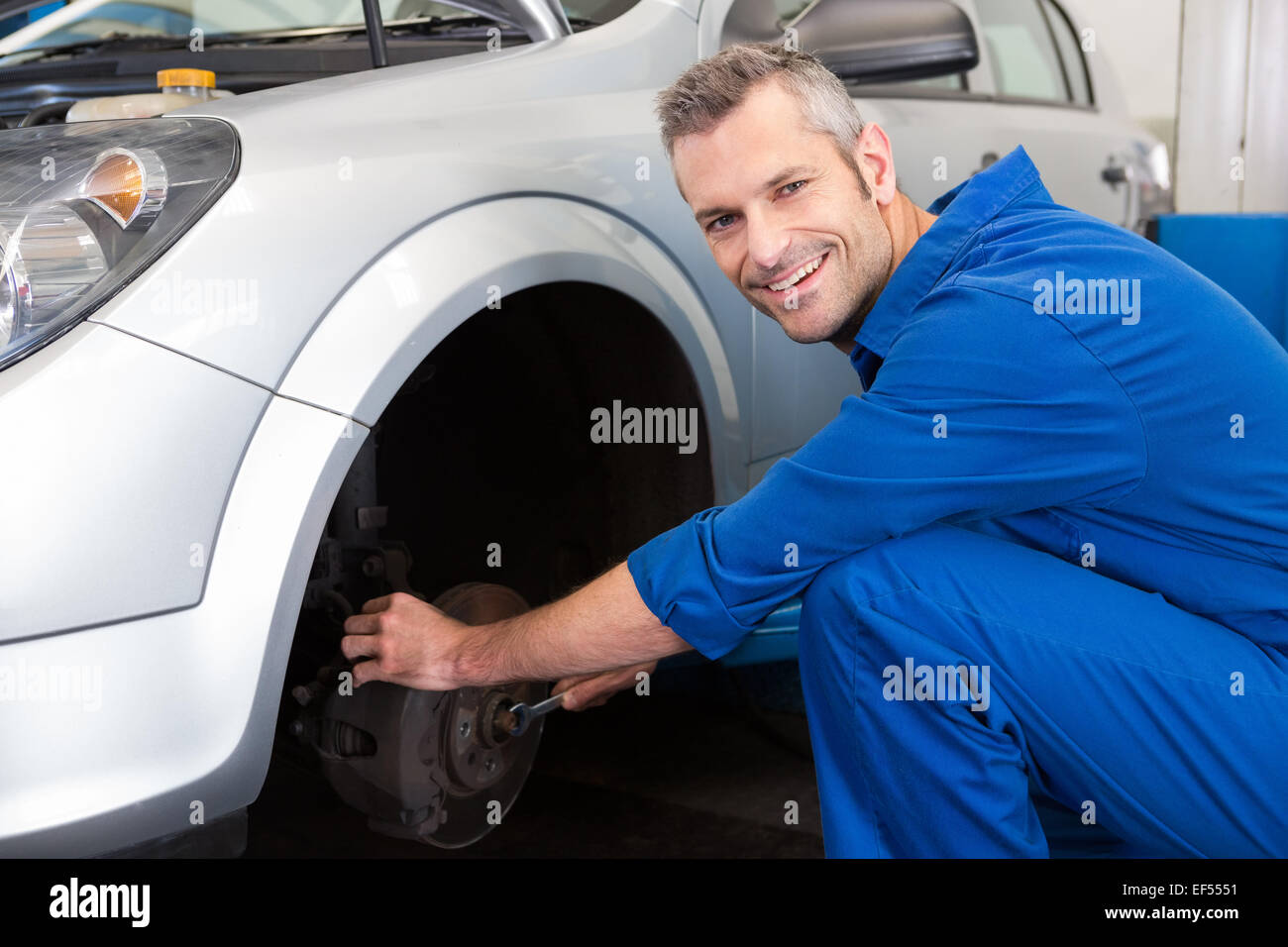Smiling mechanic adjusting the wheel Stock Photo - Alamy