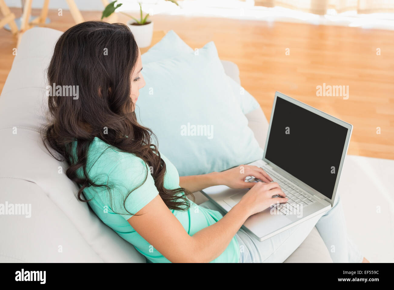 Smiling brunette using her laptop on sofa Stock Photo - Alamy