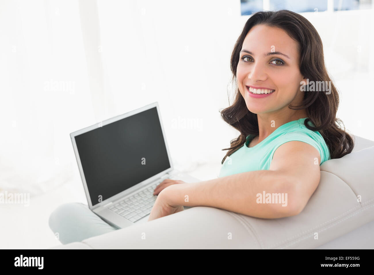 Brunette using her laptop on sofa Stock Photo - Alamy