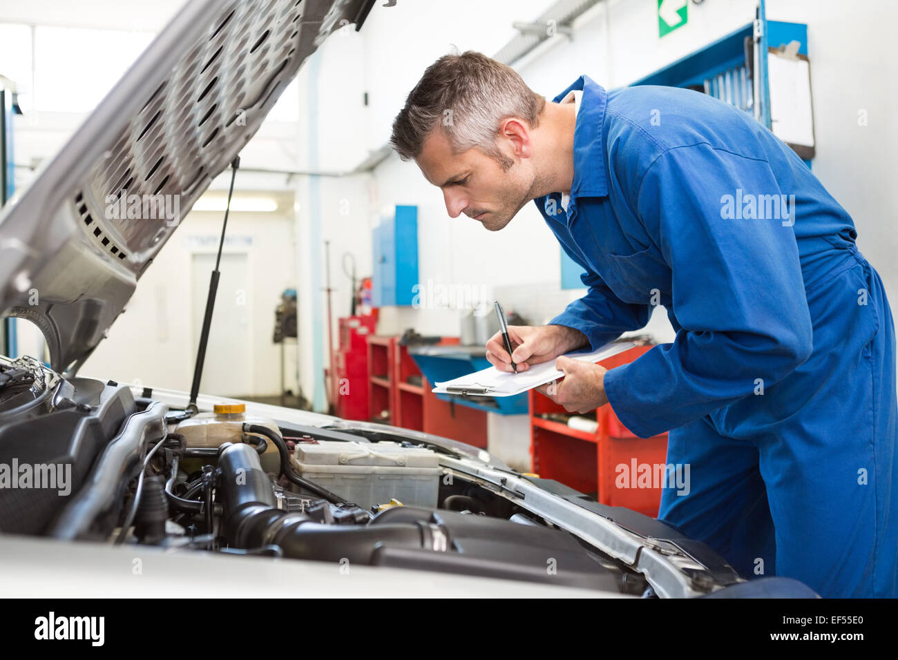 Mechanic examining under hood of car Stock Photo Alamy