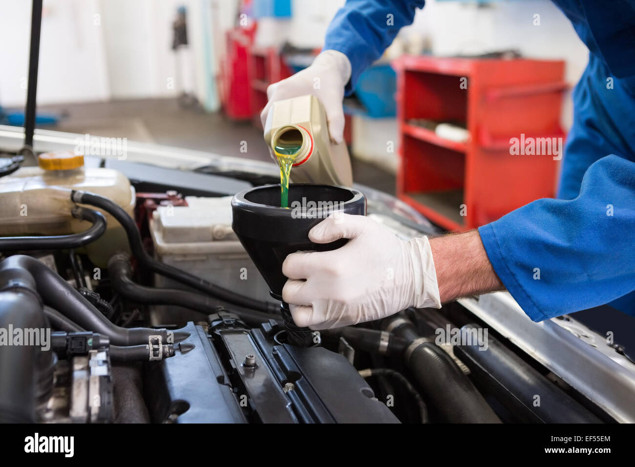 Mechanic pouring oil into car Stock Photo - Alamy