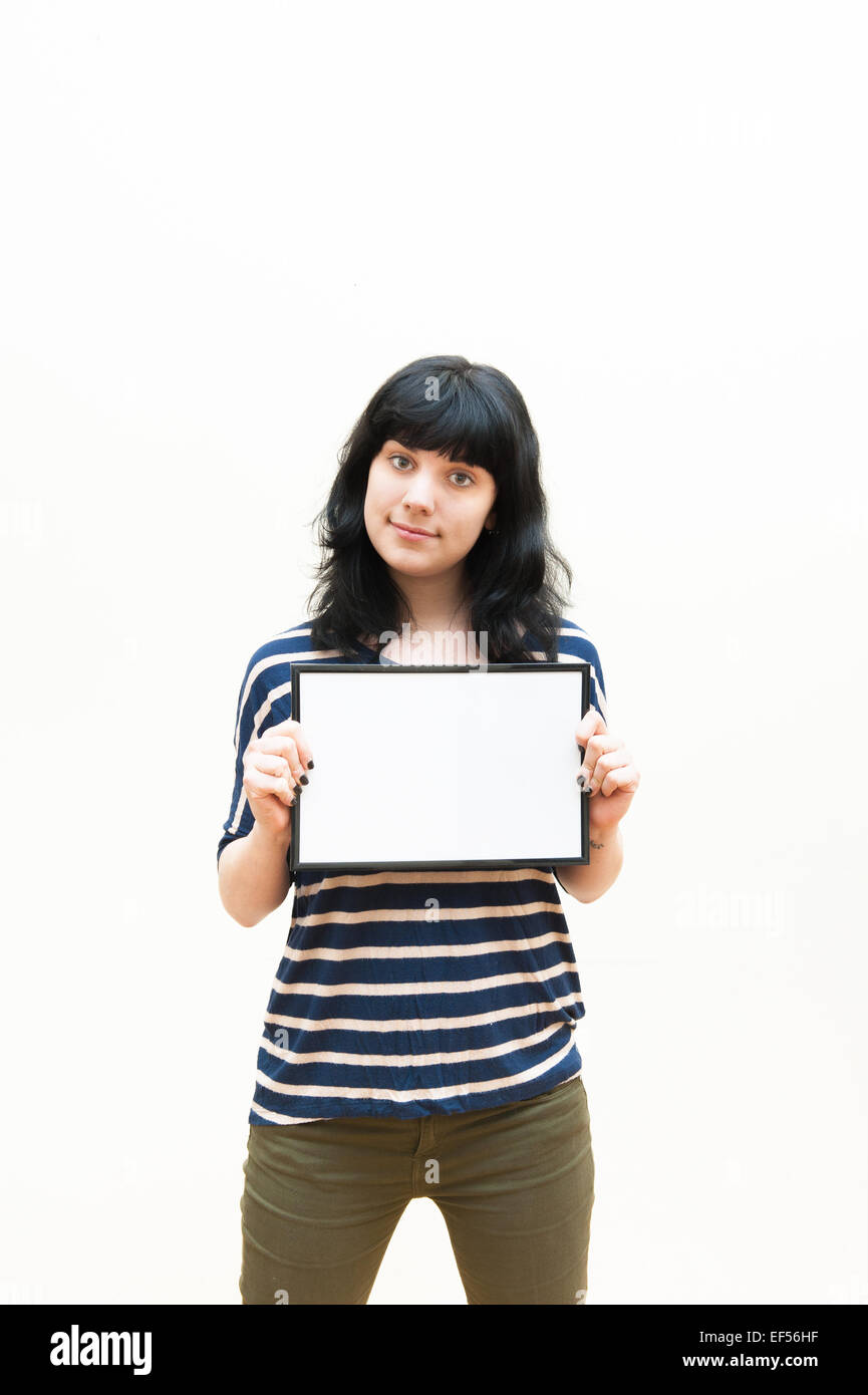 Pretty brunette girl casual clothes showing blank picture frame on white background Stock Photo