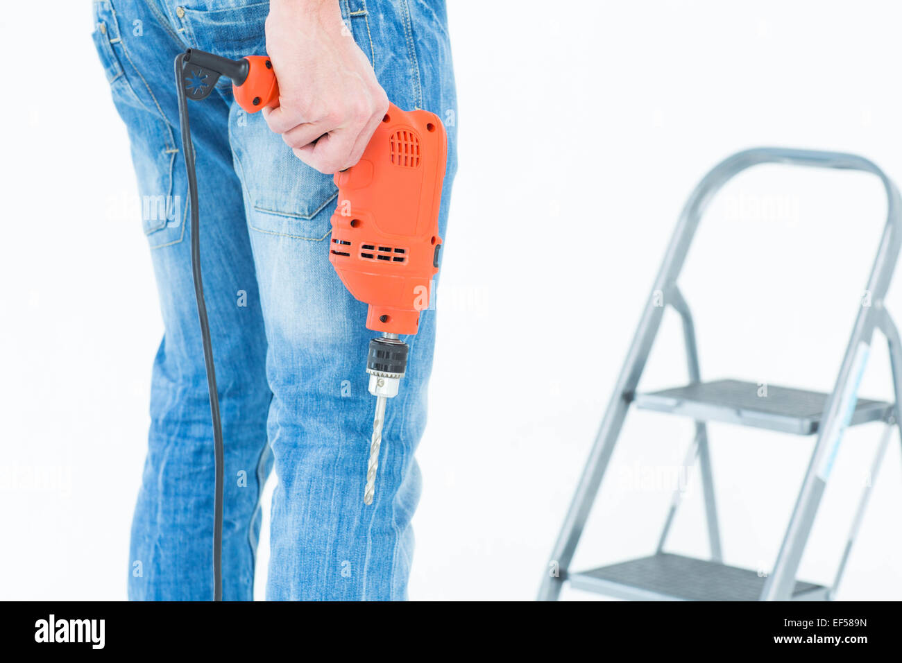 Worker holding drill in front of step ladder Stock Photo