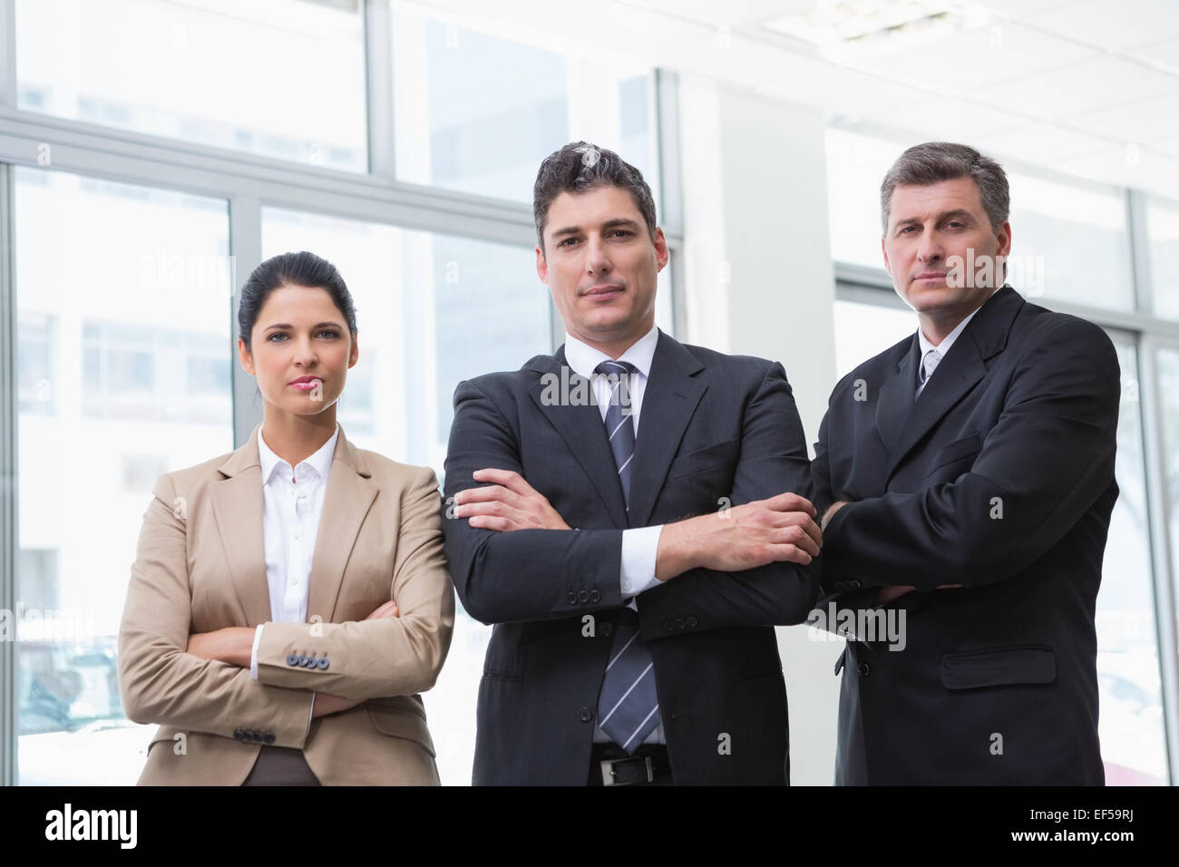 Serious business team standing with arms crossed Stock Photo - Alamy