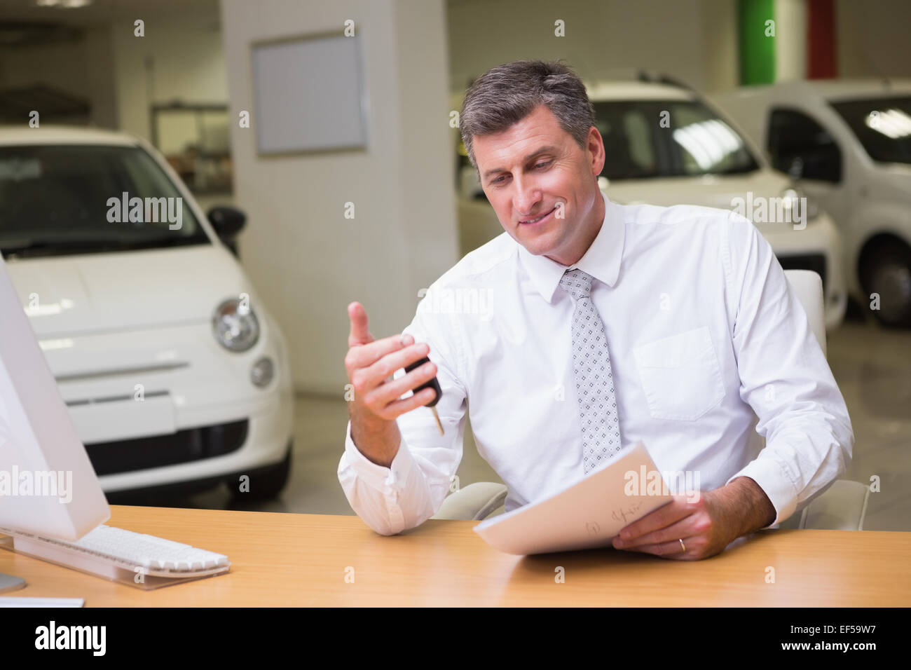 Smiling salesman holding car key and a document Stock Photo - Alamy