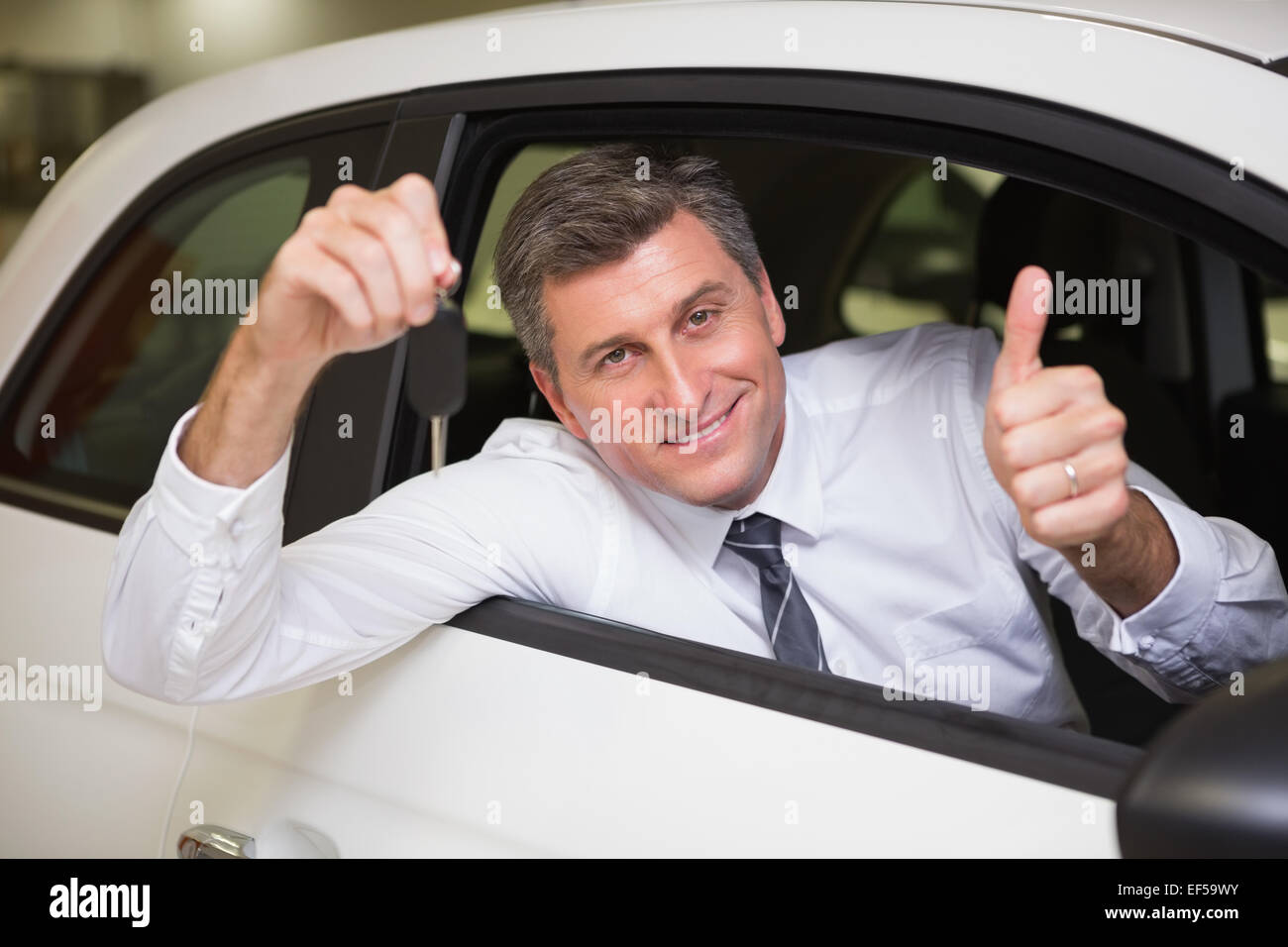 Smiling man holding a car key giving thumbs up Stock Photo - Alamy