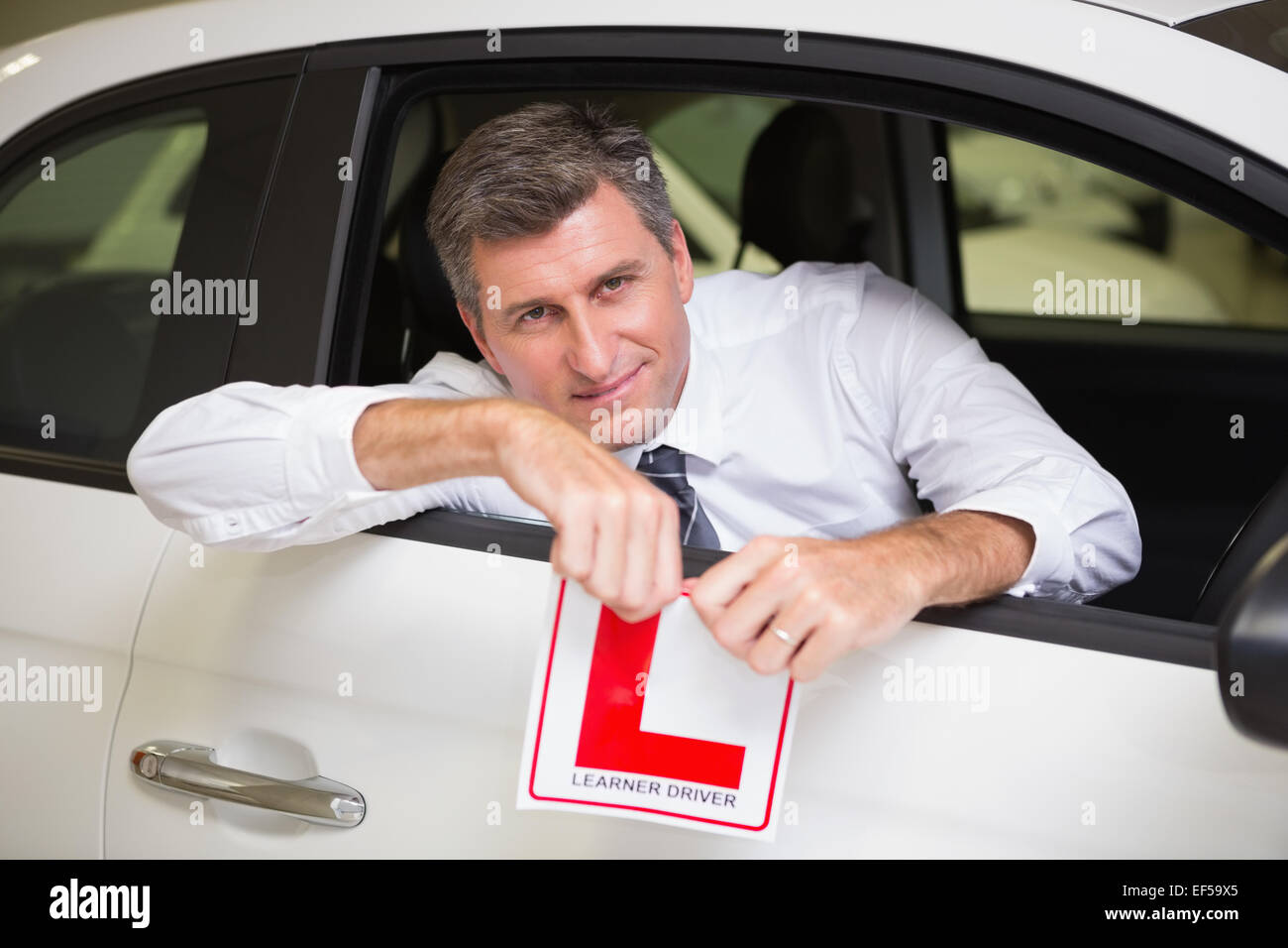Cheerful male driver tearing up his L sign Stock Photo - Alamy