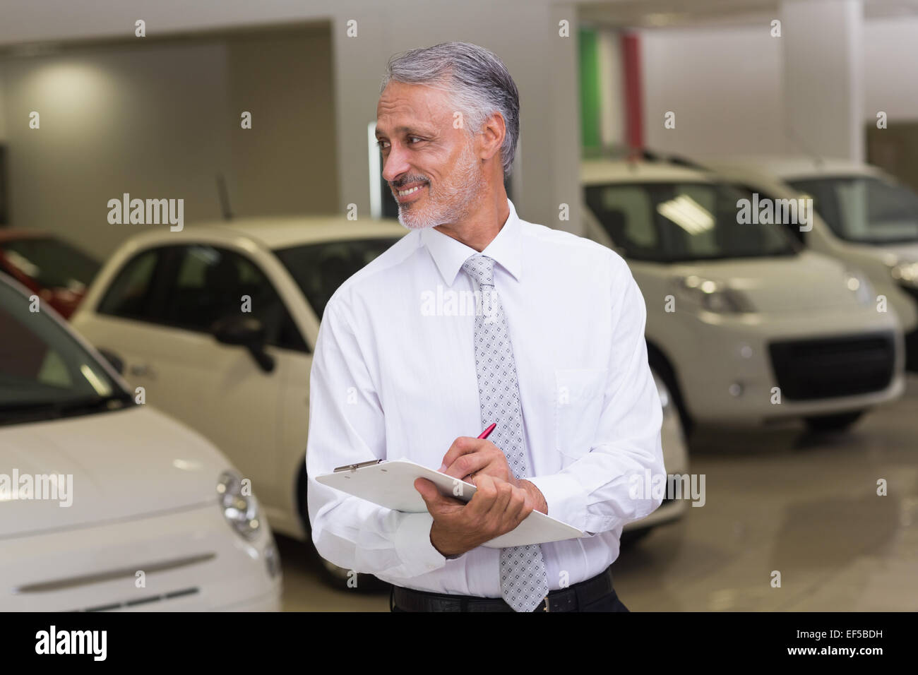 Smiling businessman writing on clipboard Stock Photo - Alamy