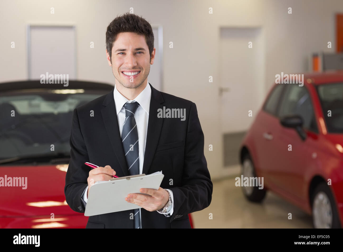 Smiling businessman writing on clipboard Stock Photo - Alamy