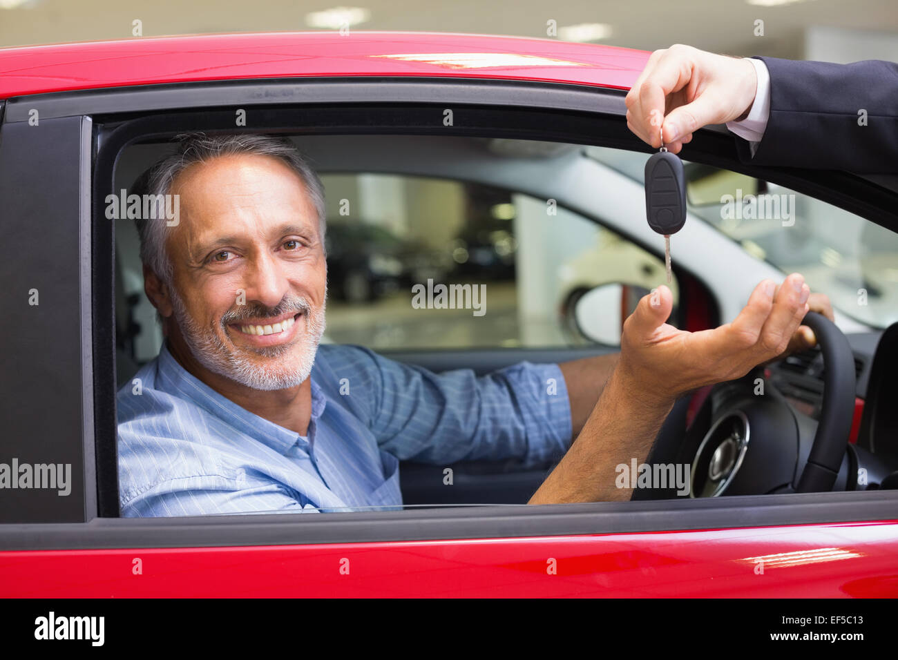 Smiling man driving a car while salesman his giving key Stock Photo - Alamy