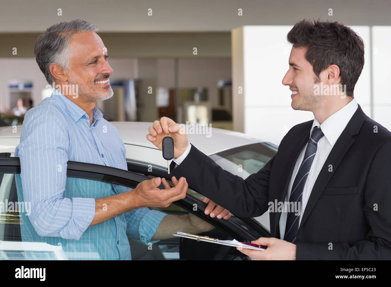 Smiling businessman giving car key to happy customer Stock Photo - Alamy