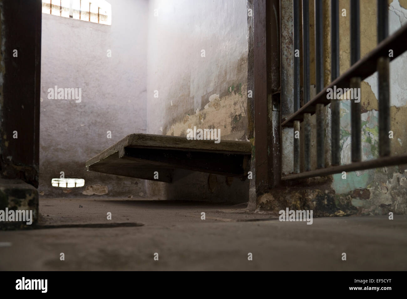 Looking into an old prison cell - concrete bed and very small window, Malaysia Stock Photo