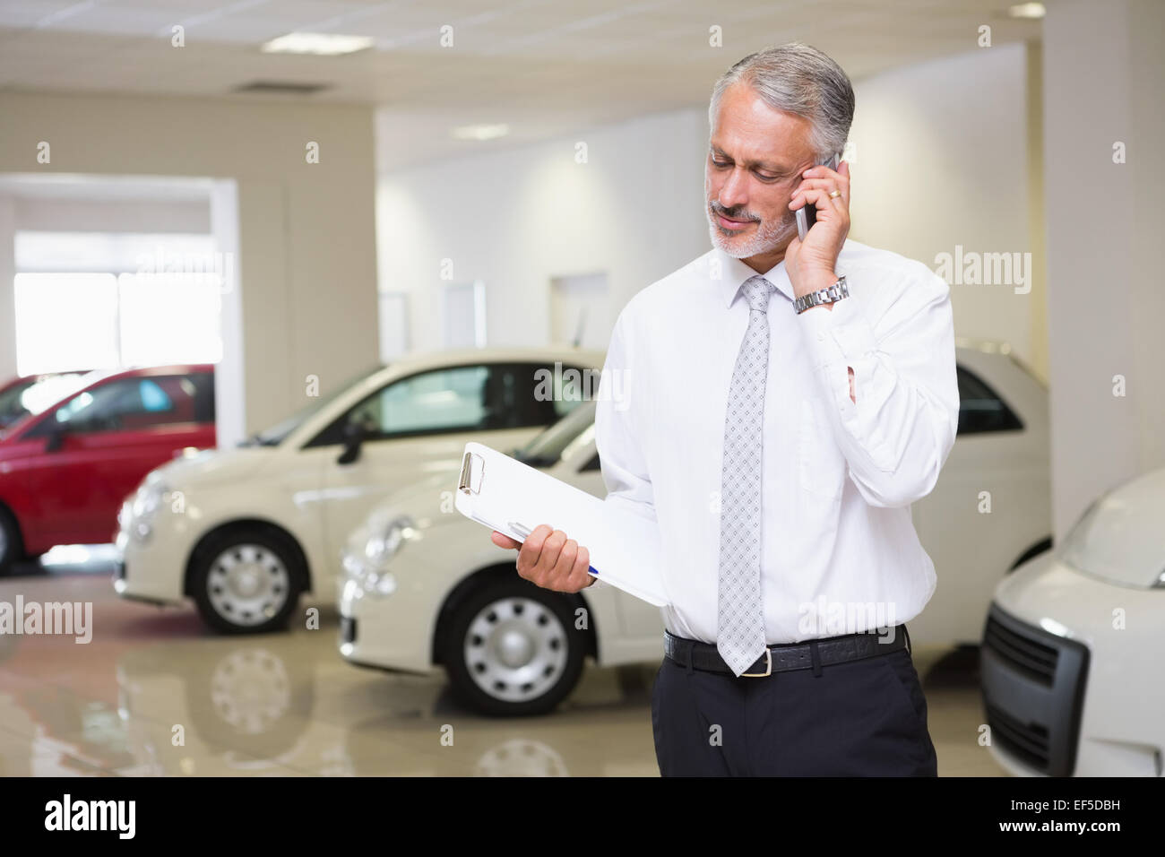 Smiling businessman on the phone holding clipboard Stock Photo - Alamy