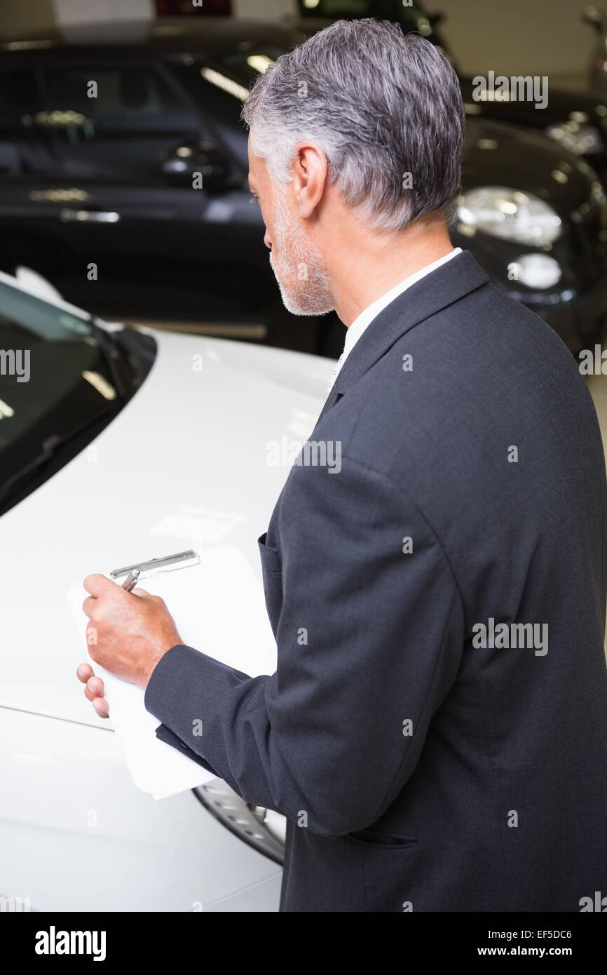 Serious businessman writing on clipboard Stock Photo - Alamy