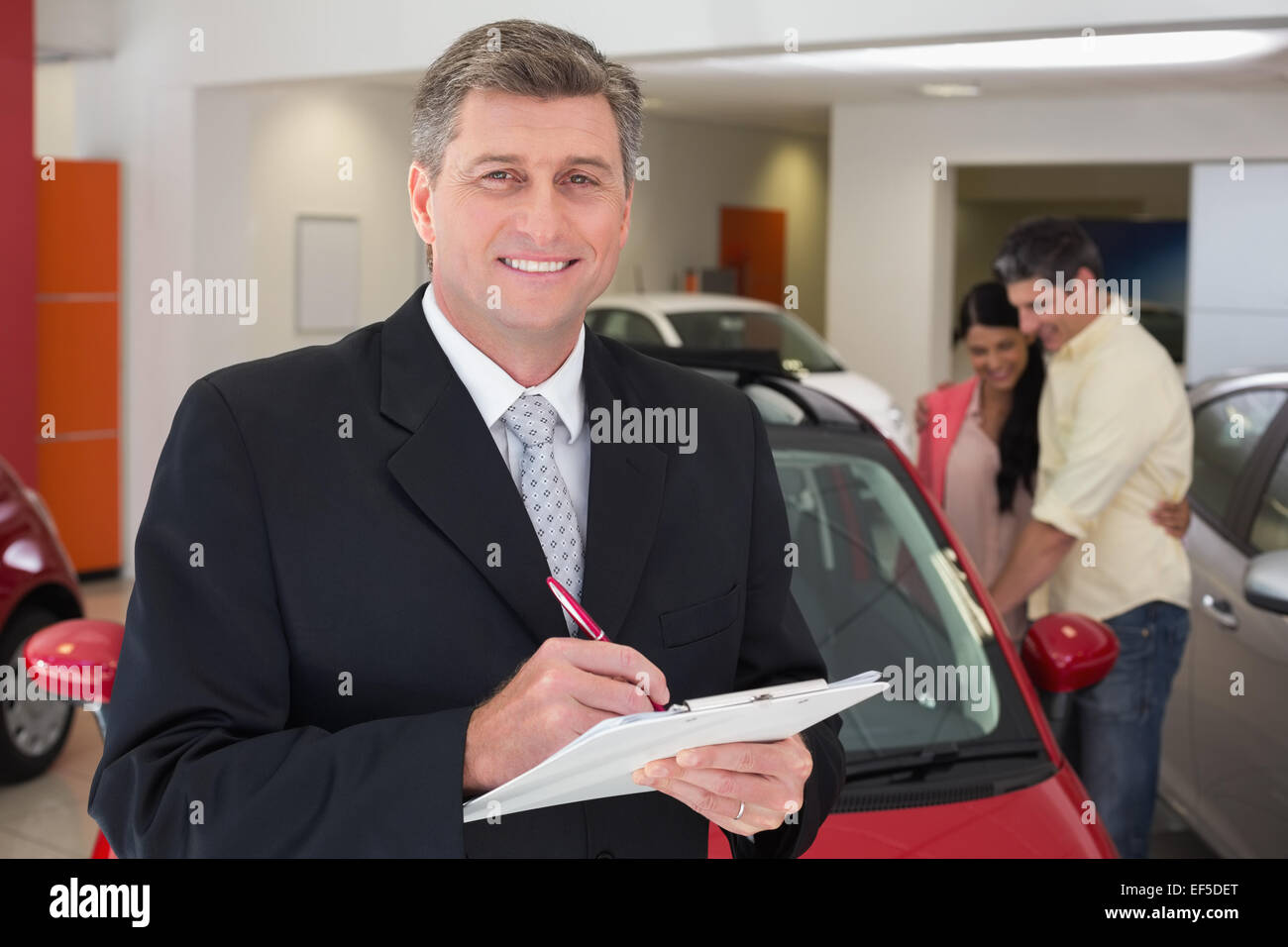 Smiling businessman writing on clipboard Stock Photo - Alamy
