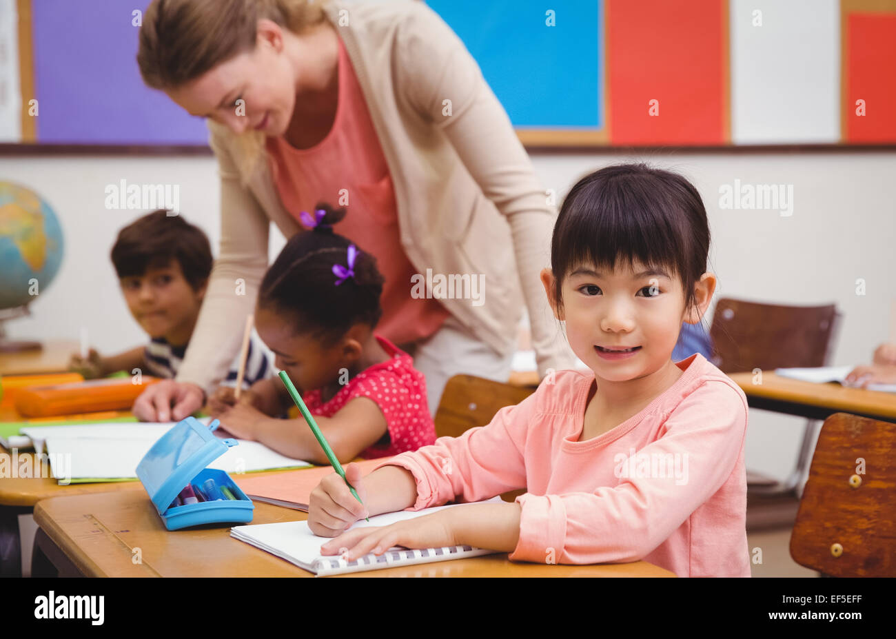 Cute pupil smiling at camera in classroom Stock Photo - Alamy