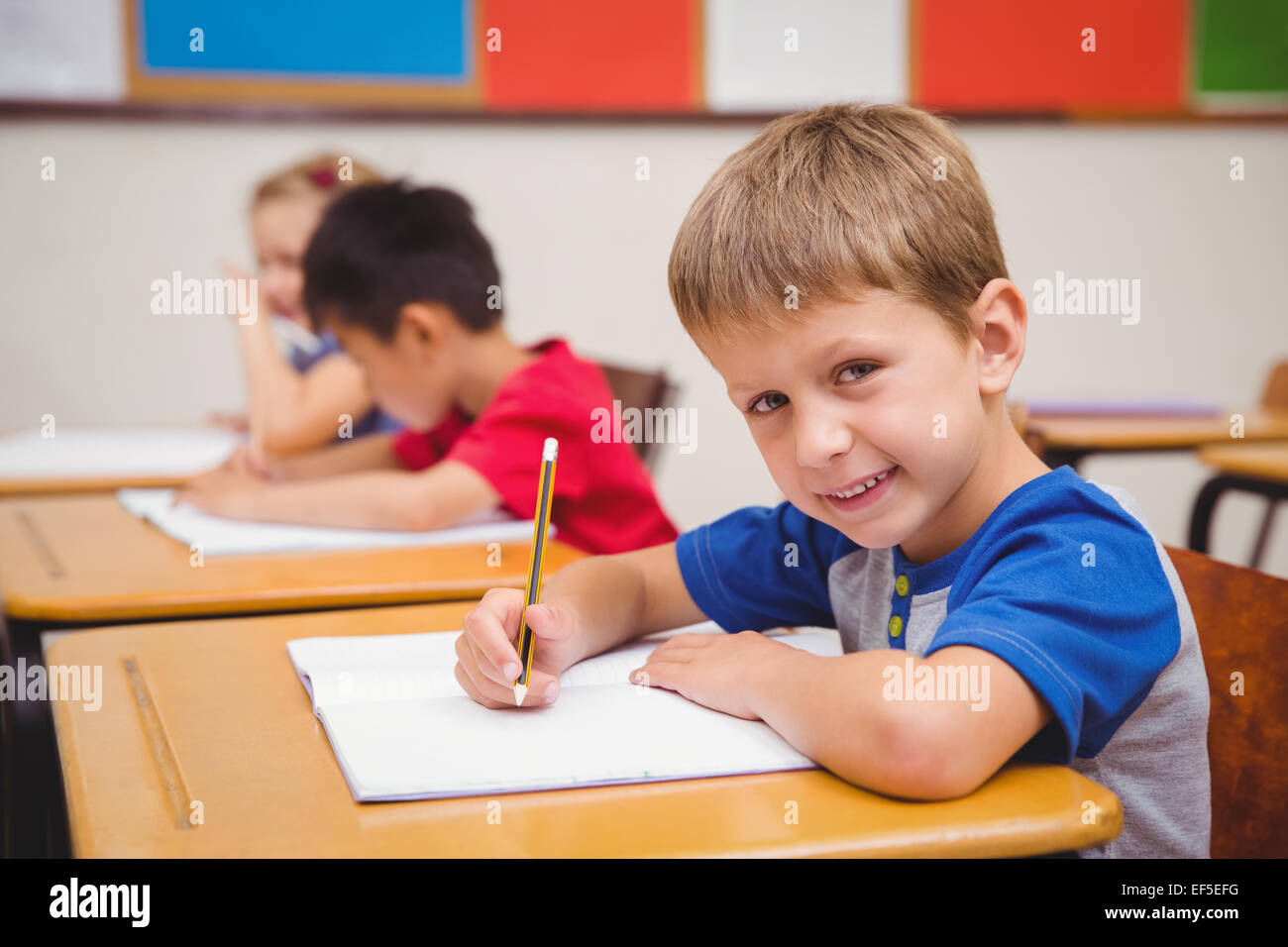 Cute pupil smiling at camera in classroom Stock Photo - Alamy