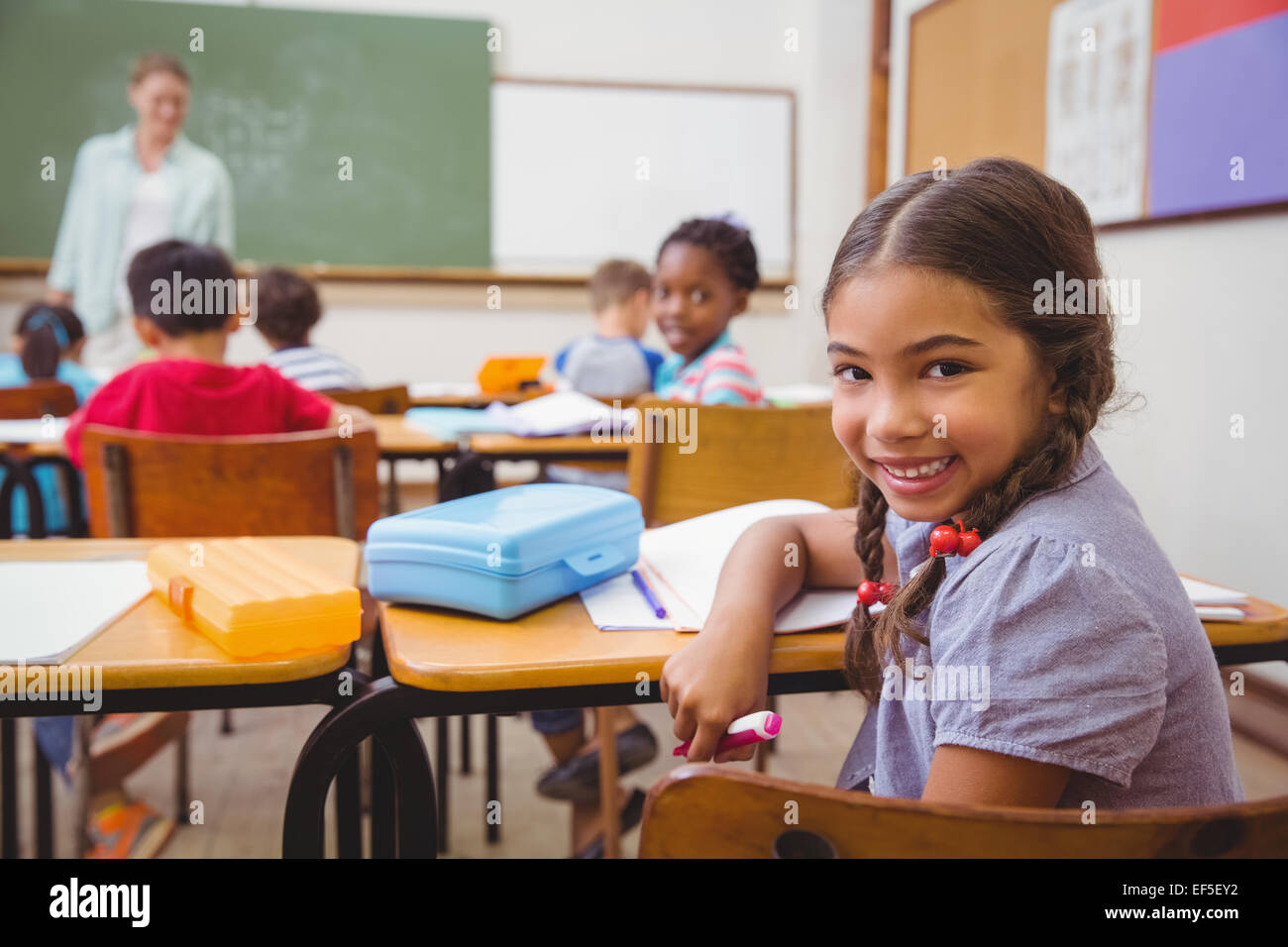 Cute pupil smiling at camera in classroom Stock Photo - Alamy