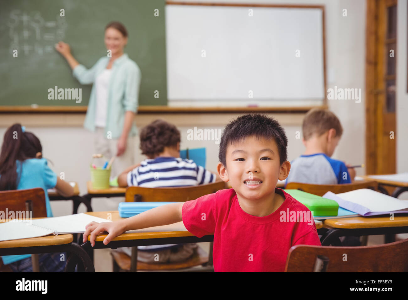 Cute pupil smiling at camera in classroom Stock Photo - Alamy