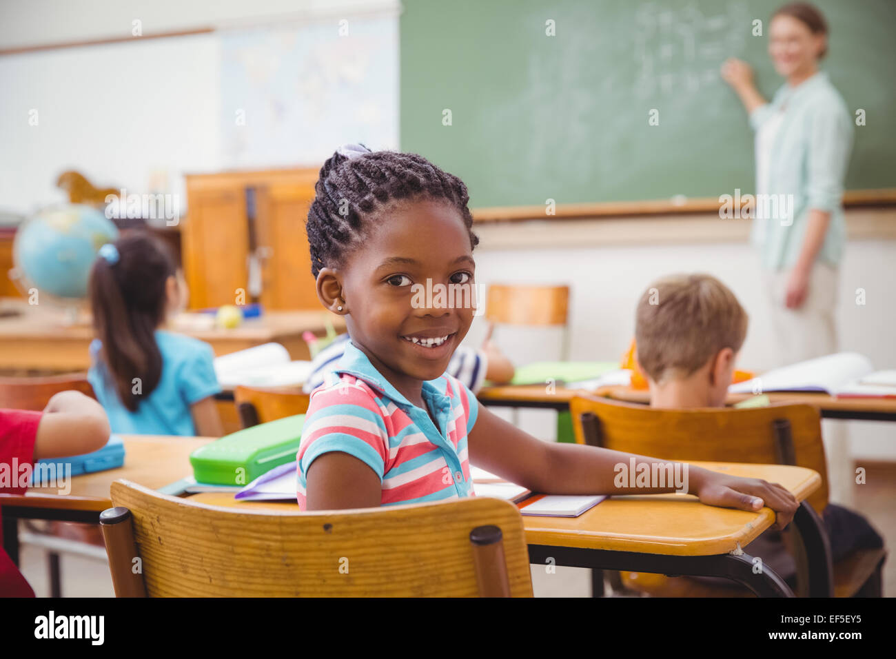 Cute pupil smiling at camera in classroom Stock Photo - Alamy