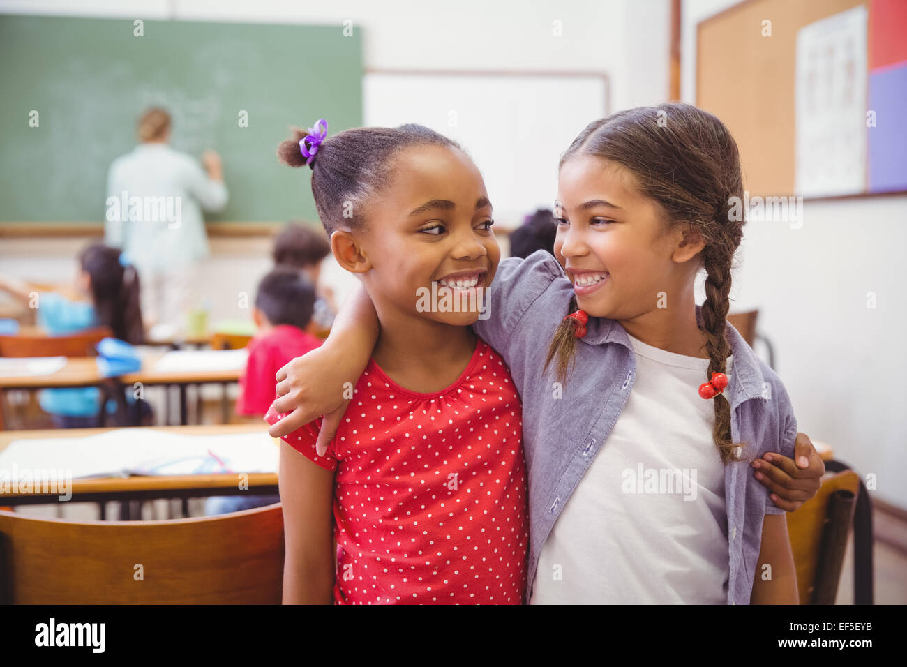 Cute pupils smiling at camera in classroom Stock Photo - Alamy