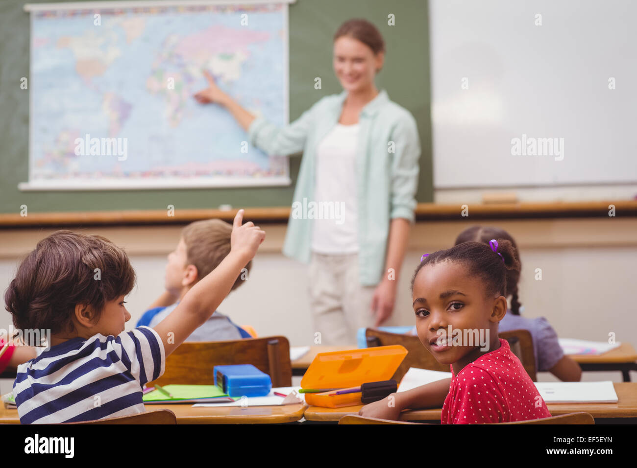 Cute pupil smiling at camera at his desk in classroom Stock Photo - Alamy