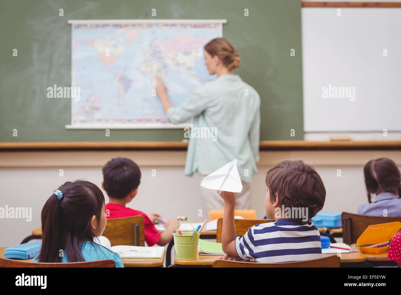 Naughty pupil about to throw paper airplane in class Stock Photo