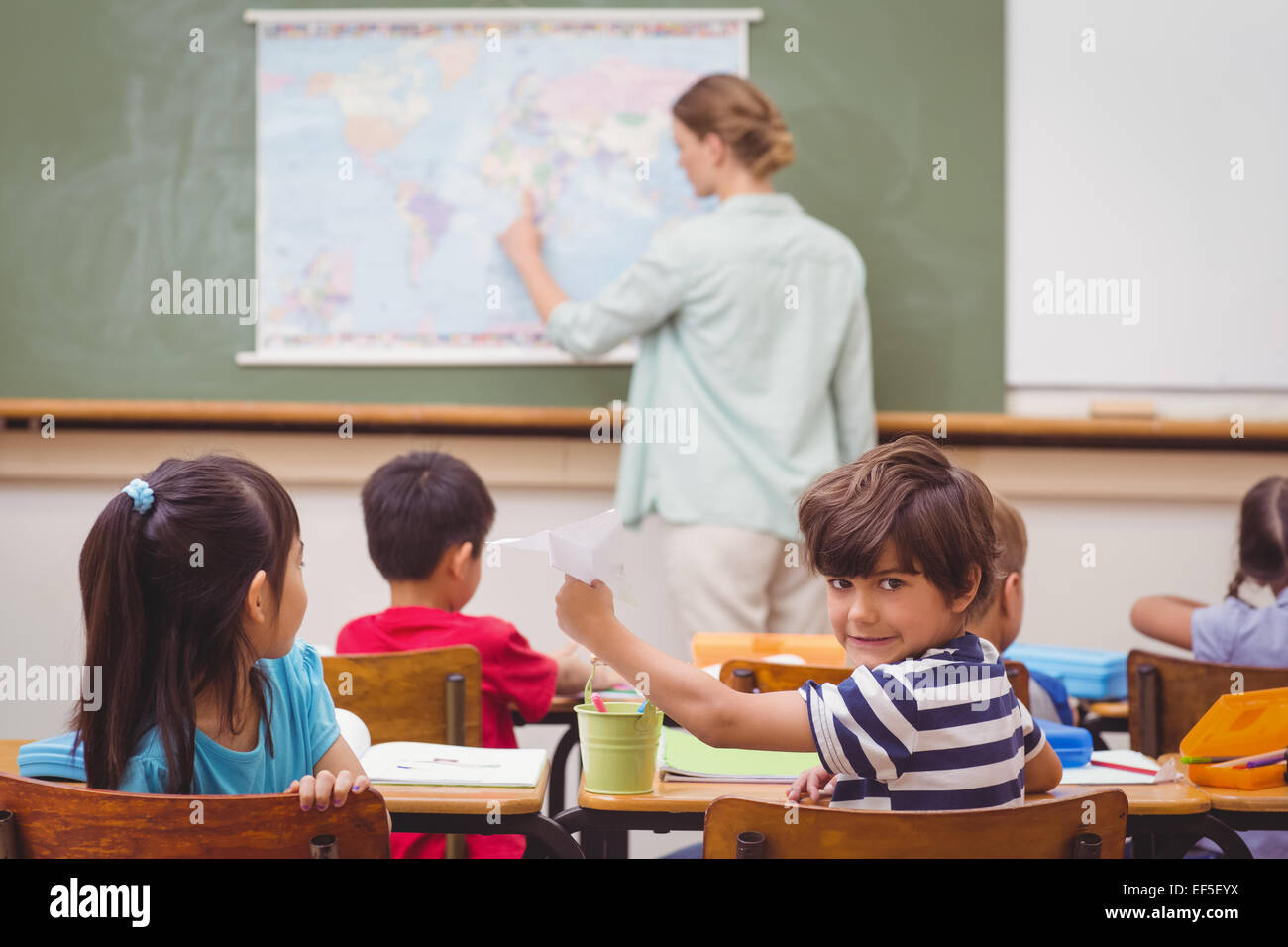 Naughty pupil about to throw paper airplane in class Stock Photo