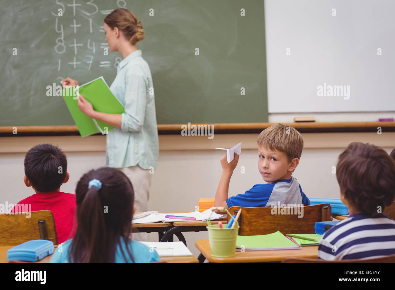Naughty pupil about to throw paper airplane in class Stock Photo