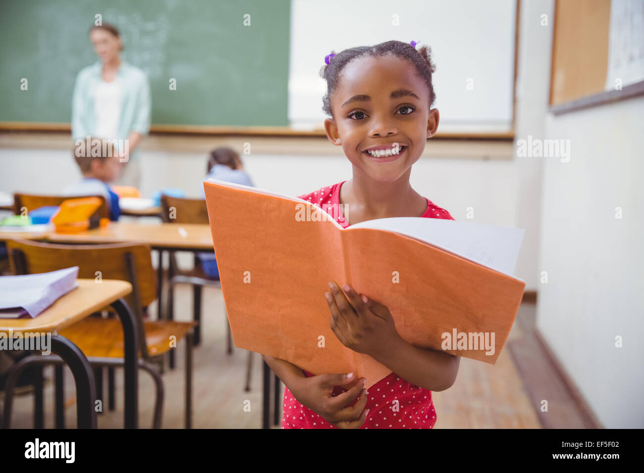 Cute pupils smiling at camera in classroom Stock Photo - Alamy
